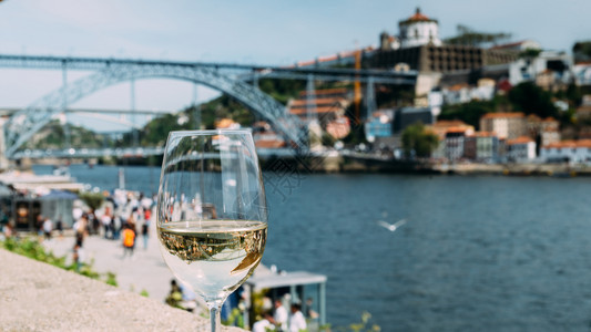 饮料葡萄牙波尔图杜罗河上俯瞰CaisdaRibeira和PontedeDomLuisI的白葡萄酒杯选择焦点玻璃上桥的反射白葡萄酒图片