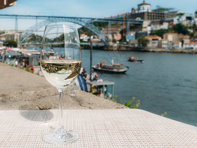城市船边缘葡萄牙波尔图杜罗河上俯瞰CaisdaRibeira和PontedeDomLuisI的白葡萄酒杯选择焦点玻璃上桥的反射白图片