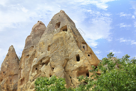 旅游在卡帕多西亚山谷地景观中的古代锥形住宅洞穴与土耳其中部的明蓝和阴云春空相对立在卡帕多西亚蜂蜜山谷古代锥形洞穴中土耳其部居民住图片