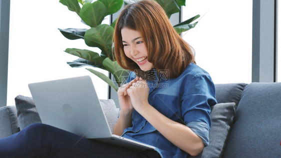 现代的在家工作参加庭办公室膝上型电脑在线会议的妇女使用笔记本的企业家女商妇坐在沙发技术上新的正常生活方式快乐女人打键盘手提电脑观图片