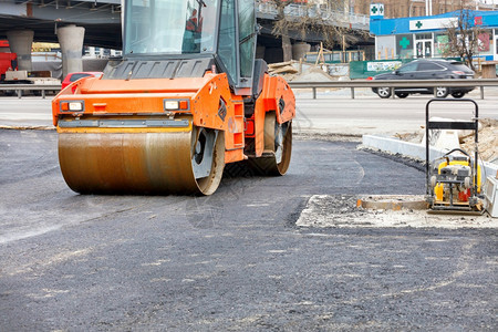 使用一个重型公路振动滚机和一个汽油振动压板在新的路段复制空间上压缩新鲜沥青道路建筑工地一个重橙振动过路和一个汽油振动压板对配成一图片