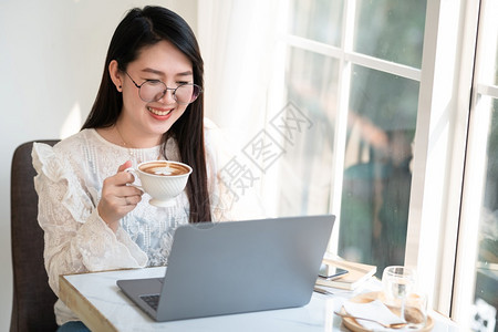 数字的女商人用笔记本电脑和咖啡店智能手机商业生活方式交流概念与笔记本电脑和智能手机一起工作的零用笔记本散工热的互联网图片