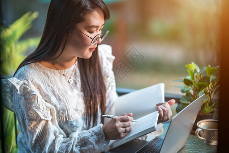 商业女人用笔记本电脑和咖啡杯及智能手机在咖啡店商业生活方式做零用笔记的散工在网吧美丽的信息教育图片