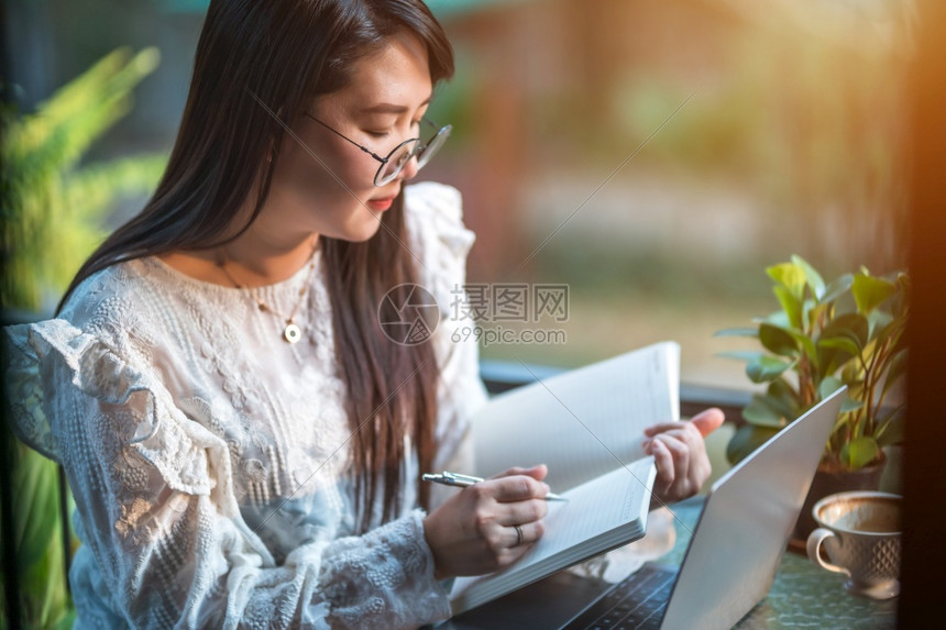 商业女人用笔记本电脑和咖啡杯及智能手机在咖啡店商业生活方式做零用笔记的散工在网吧美丽的信息教育图片