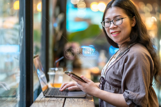 阅读女商业人用笔记本电脑与咖啡杯一起工作在咖啡馆商务生活方式上撰写关于智能手机临时空闲消息的讯写作图片