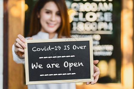 门新冠超过小企业主握着手用Covid19的文字向黑板展示Covid19已经结束我们在咖啡店前是开放牌子在Covid走了之后又恢复图片