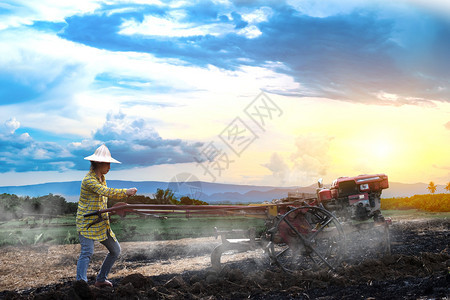 农场播种中耕机利用步行拖拉在美丽的天云下雨并在泰国农村边山上晒太阳用步行拖拉机耕种稻田植水作物泰国农村一带的山顶是美丽天空云和日图片