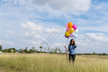 生活女人拿着气球在绿色草地白云和蓝天空上奔跑快乐轻松的天空手拿着充满活力的空气球在生日派对上欢快的盛宴玩女畅快图片