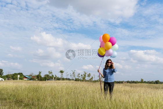 生活女人拿着气球在绿色草地白云和蓝天空上奔跑快乐轻松的天空手拿着充满活力的空气球在生日派对上欢快的盛宴玩女畅快图片