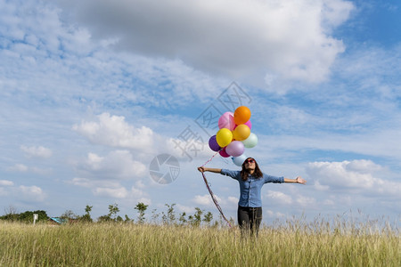 女户外人拿着气球在绿色草地白云和蓝天空上奔跑快乐轻松的天空手拿着充满活力的空气球在生日派对上欢快的盛宴玩飞行图片