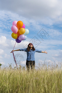 生活裙子女人拿着气球在绿色草地白云和蓝天空上奔跑快乐轻松的天空手拿着充满活力的空气球在生日派对上欢快的盛宴玩人们图片