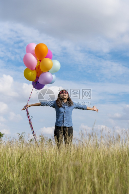 生活裙子女人拿着气球在绿色草地白云和蓝天空上奔跑快乐轻松的天空手拿着充满活力的空气球在生日派对上欢快的盛宴玩人们图片