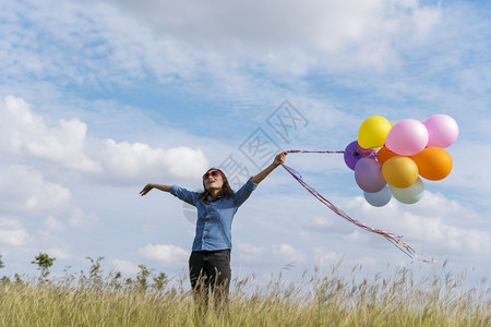 人们自然女拿着气球在绿色草地白云和蓝天空上奔跑快乐轻松的天空手拿着充满活力的空气球在生日派对上欢快的盛宴玩生活图片