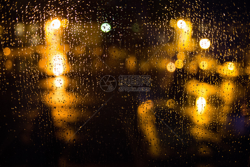 火炬哭清晨晚上在窗户下雨家门口晚上或在水外面下雨玻璃露水湿玻璃表面点水起城市的灯光在雨滴时闪耀圆形的图片