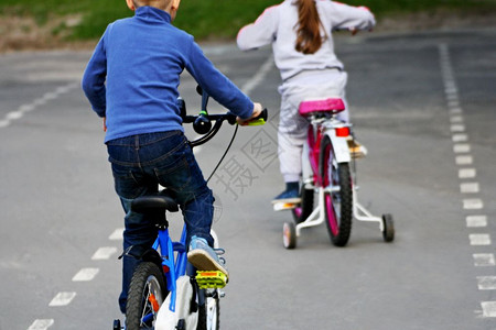 沥青滑板户外运动孩子们骑自行车的男孩追上了女运输图片