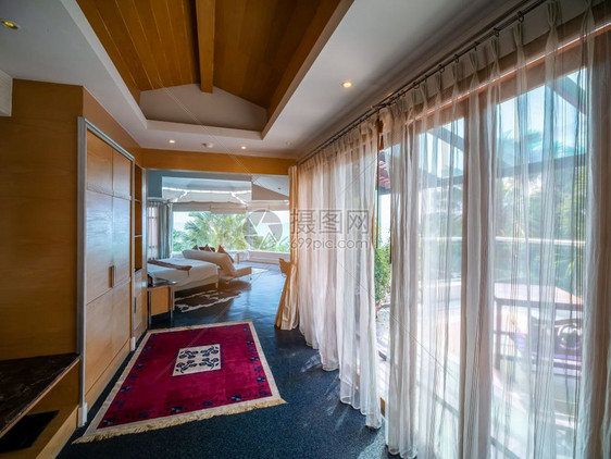 豪华房间装饰室内周围有棕色木制家具玻璃窗外观海滩和泰国旅馆度假胜地室建筑学棕榈睡觉图片