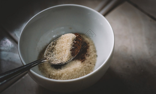 喝将糖和即时咖啡粉用茶匙测量成一个白色碗准备使Dalgona咖啡泡沫成为一汤匙糖和咖啡混合物贴近视线的成分早餐桩图片