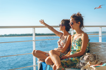 成人坐在渡轮或乘船前往岛旅游目的地暑假渡船甲板上坐着长椅的两名年轻女青朋友或姐妹在阳光明日挥舞到地平线女孩乐趣图片