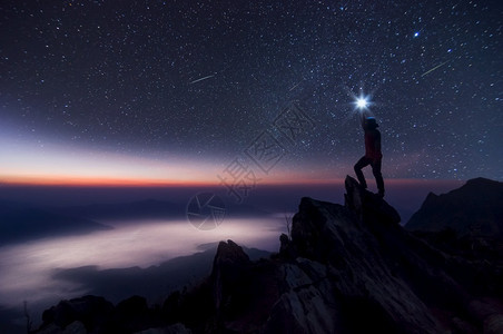 相在他的手中把光照在头顶高处站岩石山峰和银河系上成功胜利获领先导概念高等音象上面是噪领袖男人握住图片