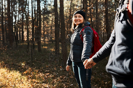 草地两人手握双在度假日渡时享受旅行Hikers与背包一起走在森林路上阳光明媚的一天上走在森林道路时间探索图片