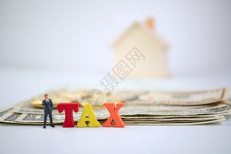 文件现金利润图与木材TAX字相对站立的商人钞票金币和木屋上的TAX字词背景纳税福利或强制金融收费的概念图片