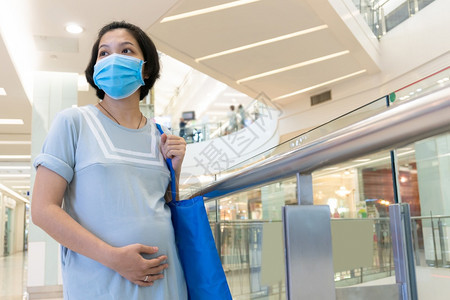 母亲预期亚洲孕妇在购物中心保护自己防止受冠状感染并佩戴面罩和摸肚子的新正常生活概念新的正常生活概念新普通生活概念图片