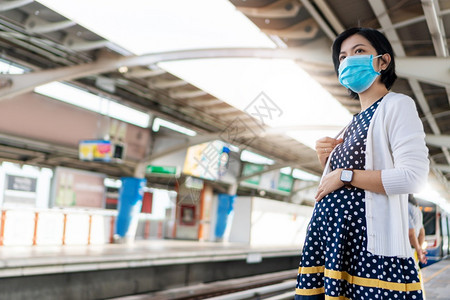 运输身戴面罩等待上天列车的亚裔怀孕妇女在大流行护理期间在公共交通中为年轻母亲服务时戴着面罩在新的正常状态和社会偏僻下提供保健服务图片