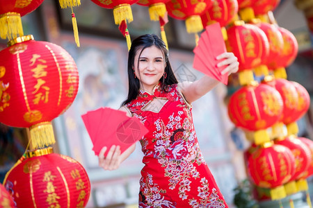 女身着青山传统红衣装饰的亚洲妇女手握红色信封和灯笼上面写着中文字祝福是新年的福分之啊问候快乐的图片