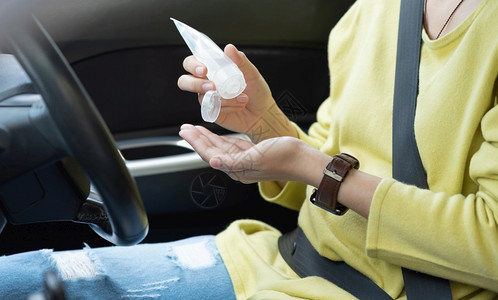 身穿绿色或黄衬衫的亚洲妇女在驾驶汽车前用手洗净剂凝胶在掌上戴保护面具以防止冠状或科罗纳天关心运输图片