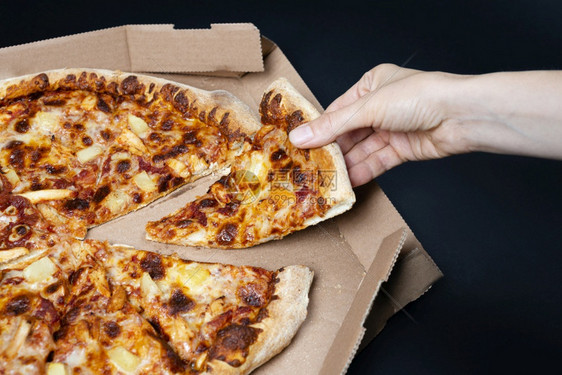 晚餐吃食物手从披萨盒中取出一片披萨夏威夷大没有一块夏威夷披萨的顶视图意大利食品街头快餐的概念手从披萨盒中取出一片披萨顶视图关于夏图片