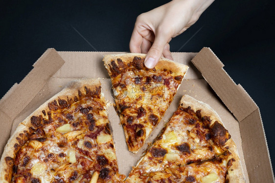 手从披萨盒中取出一片披萨夏威夷大没有一块夏威夷披萨的顶视图意大利食品街头快餐的概念顶视图关于夏威夷比萨饼意大利食品快餐的概念速地图片