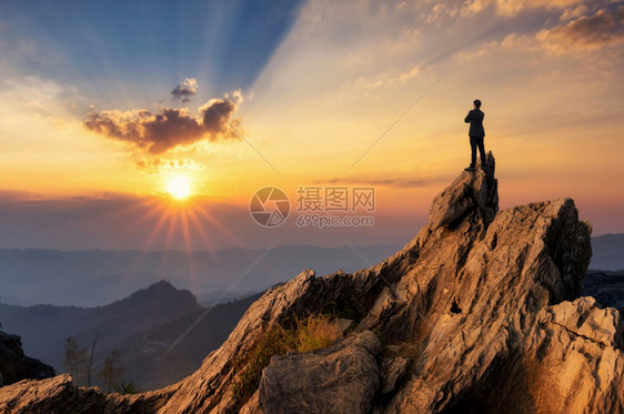 年轻商人穿着舒适的便衣夹克站在山峰顶上拥抱胸前期待未来成功竞争和领袖概念展望未来期竞争和领袖概念战略成功的解决方案图片