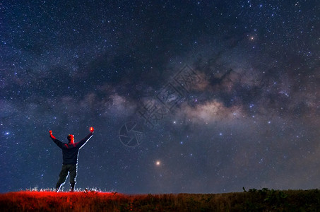 男人攀爬者或背包手持火烧岩山峰找到目标在恒星和银河系下搜索在夜晚成功或胜利领导概念高比索上面是噪音领头人星繁点图片