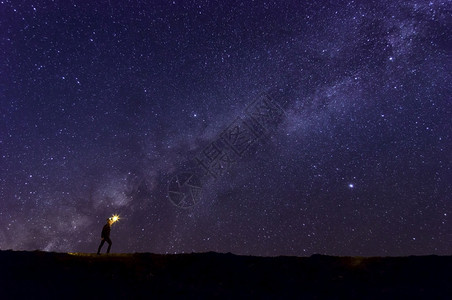 在下面日出攀登爬者或背包手持火烧岩山峰找到目标在恒星和银河系下搜索在夜晚成功或胜利领导概念高比索上面是噪音领头人图片