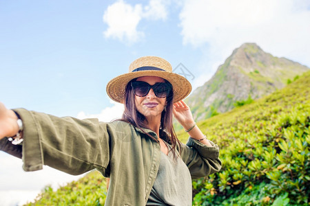 安静的自然旅游戴着帽子的美丽快乐女人在度假时山上自拍美丽的风景幸福年轻女孩在雾中深处的山上美丽年轻人图片