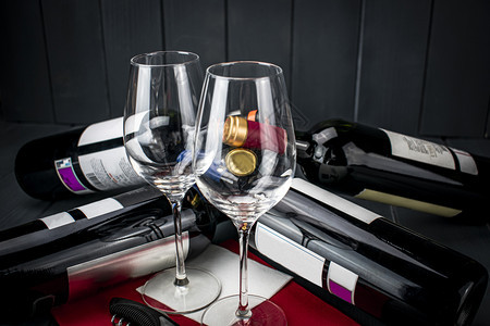优雅酿酒吧深红桌布上闪亮的玻璃杯衣橱和四瓶红葡萄酒他们躺着在地上休息以脱下衣服和品味图片