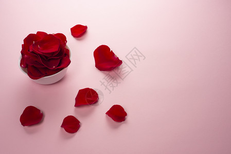 最佳草本身体白色碗中美丽的红玫瑰花瓣和嫩粉色背景中的桌子上花瓣用于香水化妆品和沐浴的玫瑰花瓣顶视图复制空间白色碗中美丽的红玫瑰花图片