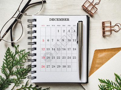 圣诞树的日历和绿枝躺在白桌上从面看特写没有人为假期做准备的概念祝贺亲戚朋友和同事圣诞树的日历和绿枝问候专业人士分支图片