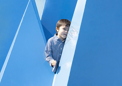 隐藏在蓝抽象的墙壁上快乐的孩子在游场上玩得开心亚裔高加索混杂种族幼童在夏天愉快地玩躲藏和到外面找寻年轻的学龄前儿童图片