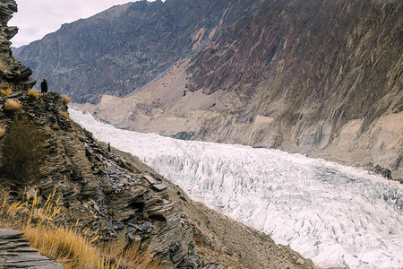 徒步旅行一个站在悬崖上看着白帕苏冰川的男人在巴基斯坦吉尔特俾提斯坦GojalHunza的卡拉科姆山脉亚洲寒冷的图片