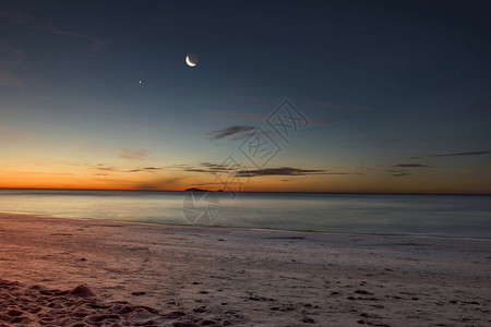 金的浪漫月亮在水上沙子新月和星在黎明时我身旁的海滩边有金色的阳光开始照亮日的月太阳即将被光遮蔽发的黑暗图片