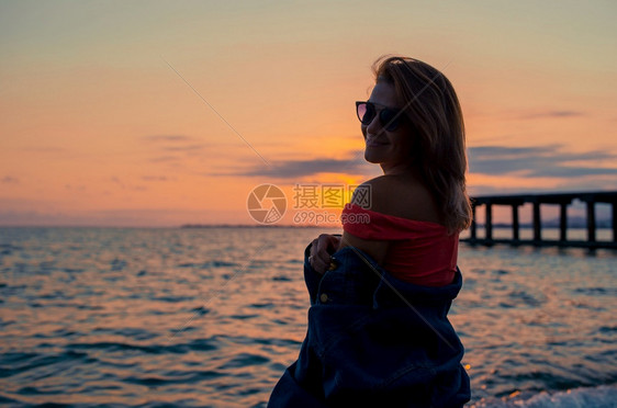 年轻美女在黄日落时热带海滨玩得开心外门时装肖像尚女孩穿着潮光太阳眼镜和牛仔夹克户外嘴唇夏天图片