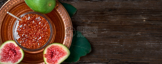 生活出去在土耳其铜盘上一个玻璃罐子里装的Fig果酱上面有一半新鲜无花果和一片叶最美的无花甜点带复制空间的黑木背景最佳图片