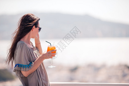 酒精米科诺斯在外咖啡厅的快乐女青年喝着美味饮料高加索旅游者享受欧洲节日令人惊叹的景象是古老城市和海边在室外咖啡厅的快乐女图片