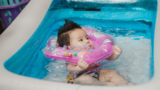 可爱女婴在装满充气的泳池里游泳图片
