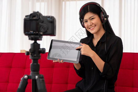 一种课VlogAsia女博客影响者坐在沙地上并录制视频博客用于教学辅导生或订阅者如何在网上创作新生活方式内容的概念耳机图片