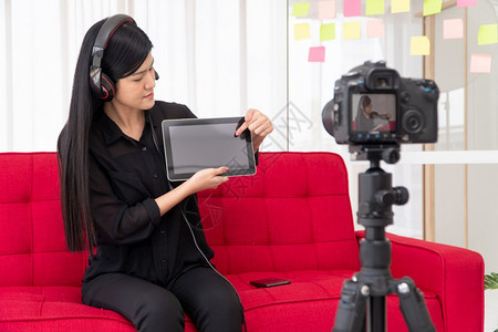 一种VlogAsia女博客影响者坐在沙地上并录制视频博客用于教学辅导生或订阅者如何在网上创作新生活方式内容的概念在家工作教育图片