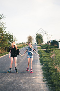 活动美丽的笑年轻女孩玩着滑溜冰在夏日共度时光快乐的图片