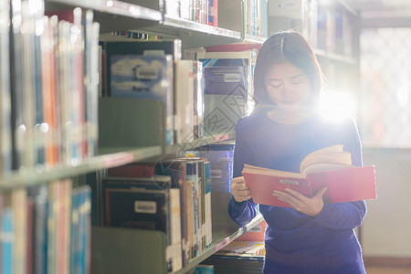 站在图书馆书架旁阅读书籍的女孩图片