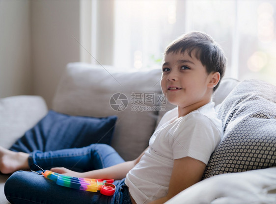 新的一个坐在沙发上快乐的小孩坐在沙发上玩着多色塑胶具在室内画像带着可爱的孩子放松并享受在家玩具新小很受孩子们欢迎坐着推图片